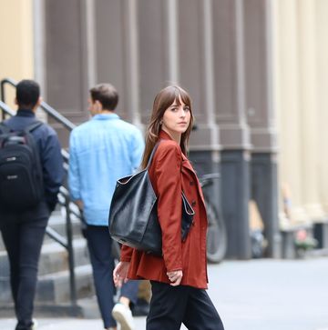 dakota johnson wearing a leather jacket and pants with a travel tote bag