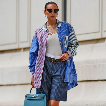 person wearing a multicolored oversized shirt and shorts carrying a teal handbag person wearing a multicolored oversized shirt and shorts carrying a teal handbag