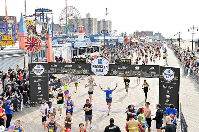 participants finishing the brooklyn half marathon on a boardwalk with amusement park in the background