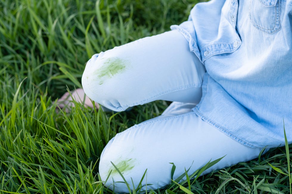 an unrecognizable person with green knees on trousers sitting on the grass. spoiled clothes. ecological methods of stain removal. outdoors. top view.