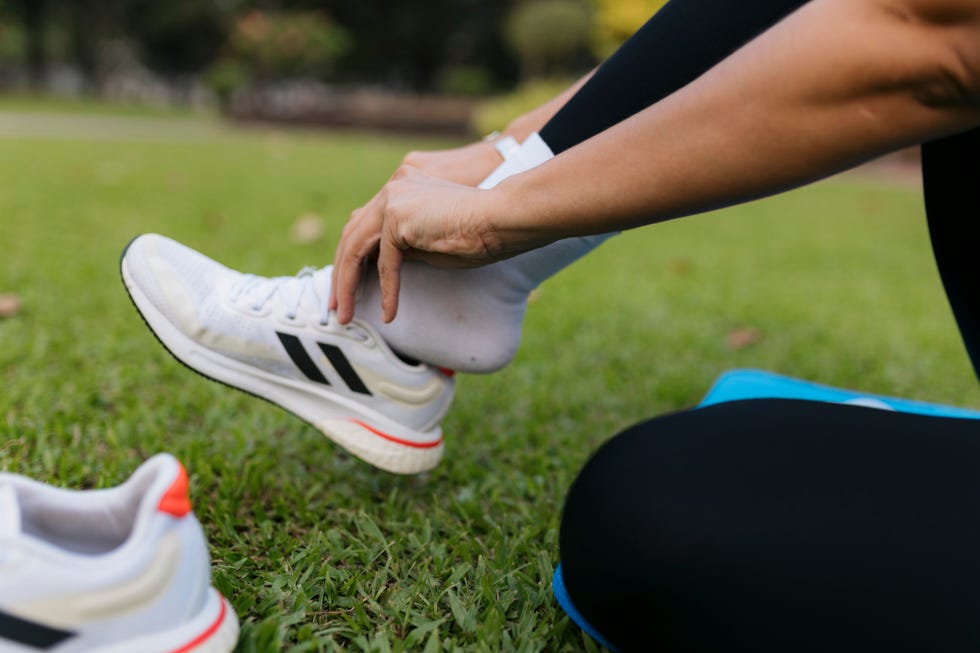 cropped shot of young woman wearing sports shoes for doing yoga at park female put on sports shoes and getting ready for yoga session at park