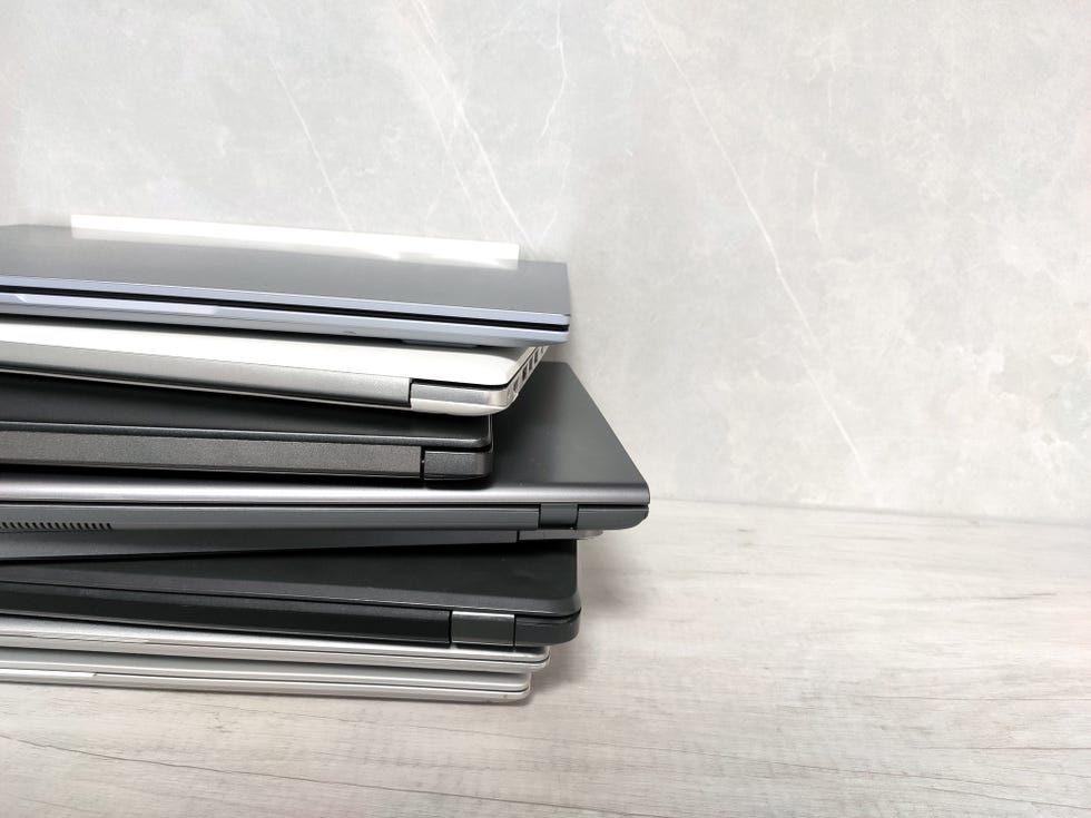 stack of pile of laptops on a gray background. many laptop computers, communications, internet, technology, equipment, tablet, netbook