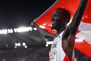 a man smiles and holds up a flag to celebrate