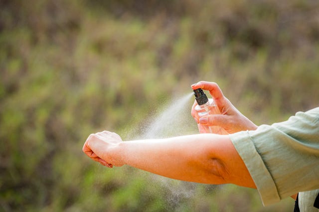 woman spraying mosquito insect repellent on her arm. protection against insects bites