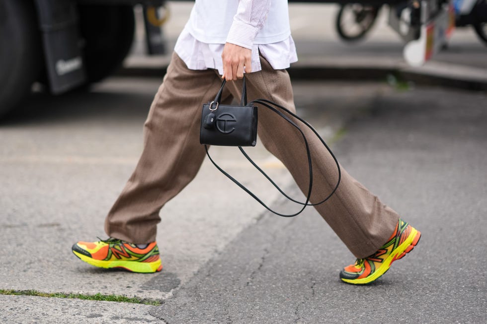 MILAN, ITALY June 15, 2024 Guests wear brown trouser pants, New Balance neon yellow orange and green sneakers during Milan Fashion Week Men's Wear Spring Summer 2025 held in Milan, Italy on June 15, 2024 Image of Edward Bartelloghetti wearing shoes, Telfar black bag, msgm outdoors