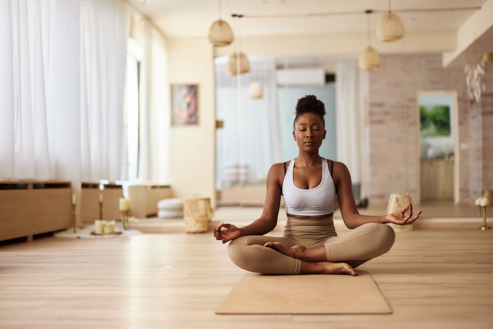 young black woman doing yoga meditation exercises in lotus position at health club. copy space.