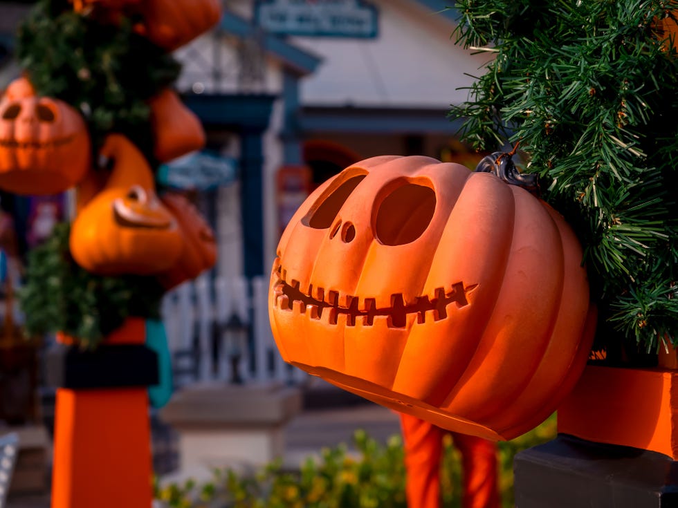 jack o lantern pumpkins with scary smiling face hanging decoration in front of a house in a small village
