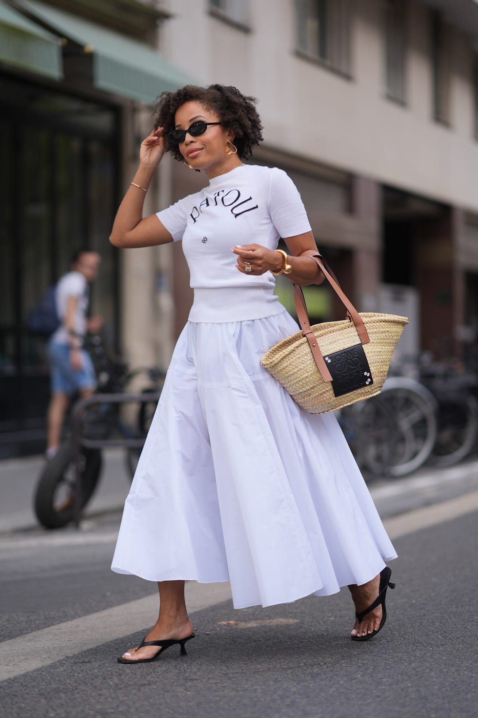 paris, france june 27 ellie delphine wears black sunglasses, gold earrings, white short sleeve patou shirt, gold bracelets, white high waisted flowy maxi skirt, dark brown leather straps basket bag, black thong flip flop shoes, outside patou, during the paris haute couture week fallwinter 2024 2025 on june 27, 2024 in paris, france photo by edward berthelotgetty images