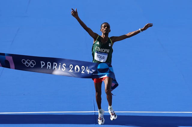 paris, france august 10 tamirat tola of team ethiopia crosses the finish line to win the gold medal during the mens marathon on day fifteen of the olympic games paris 2024 at esplanade des invalides on august 10, 2024 in paris, france photo by hannah petersgetty images