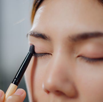 Beautiful woman applying makeup in front of the mirror at home. how to apply eyeshadow