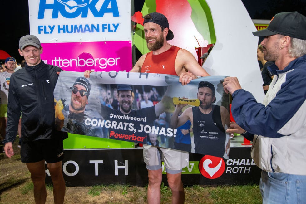22 august 2024, bavaria, roth extreme athlete jonas deichmann m holds a banner congratulating him on his new world record for the long distance triathlon at the finish line in roth deichmann wants to swim 38 kilometers, cycle 1802 kilometers and run a marathon a total of 120 times a day the previous world record stood at 105 consecutive long distances photo pia bayerdpa photo by pia bayerpicture alliance via getty images