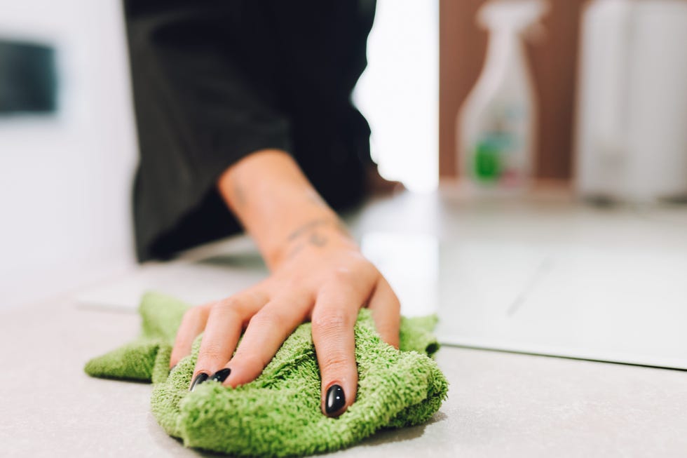 unrecognizable woman hand wiping and rubbing tabletop with green cloth