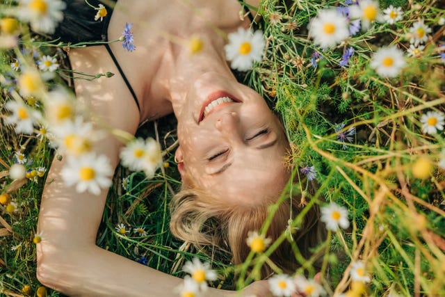 smiling woman with eyes closed lying in meadow