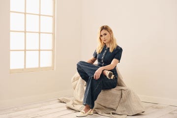 a person seated on a fabric mound in a bright minimalistic interior space