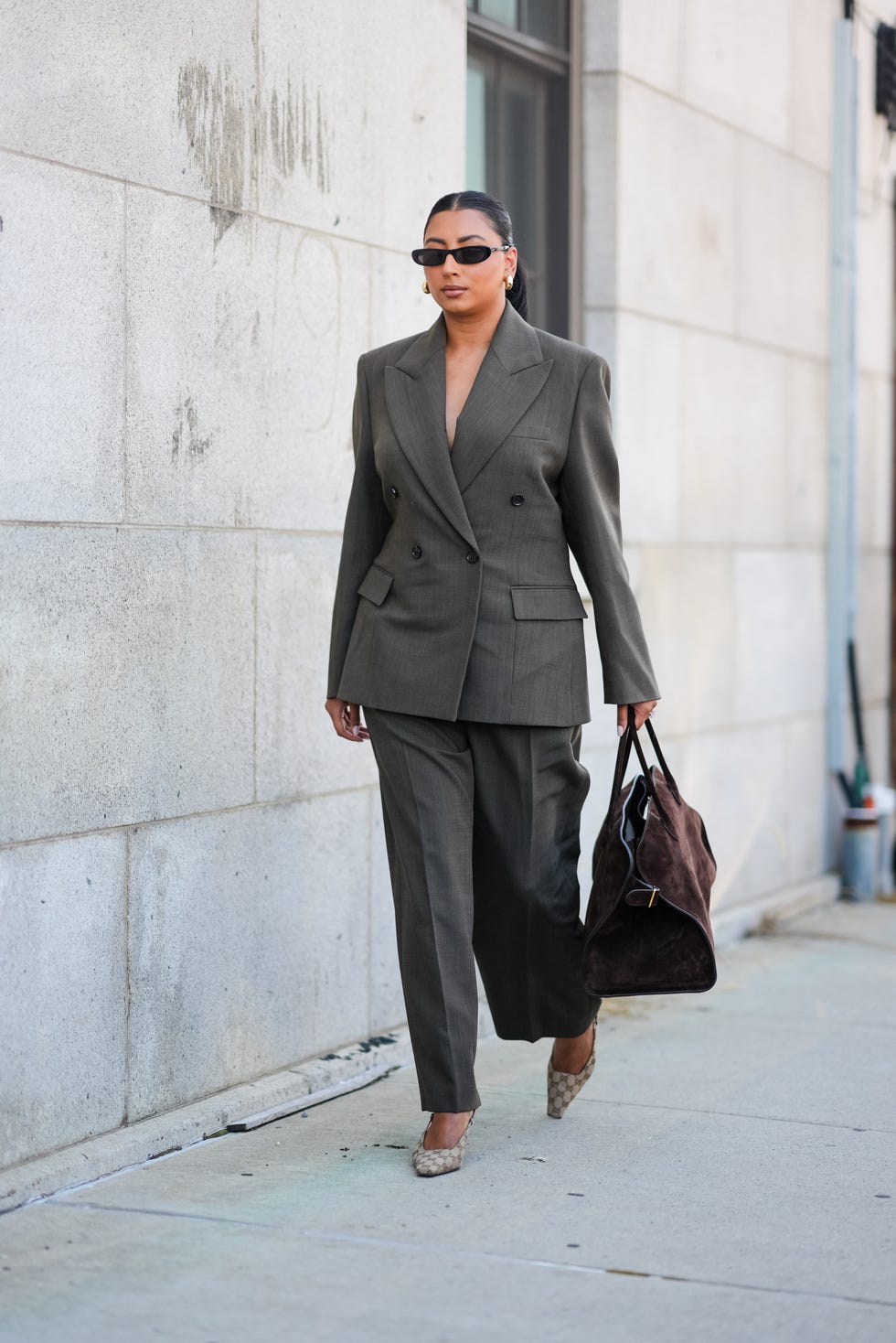 new york, new york september 10 a guest wears black sunglasses, gold earrings, dark gray blazer jacket, dark gray pants, dark brown suede the row tote bag, light gray monogram pattern gucci heels, outside cos, during the new york fashion week springsummer 2025 on september 10, 2024 in new york, new york photo by edward berthelotgetty images