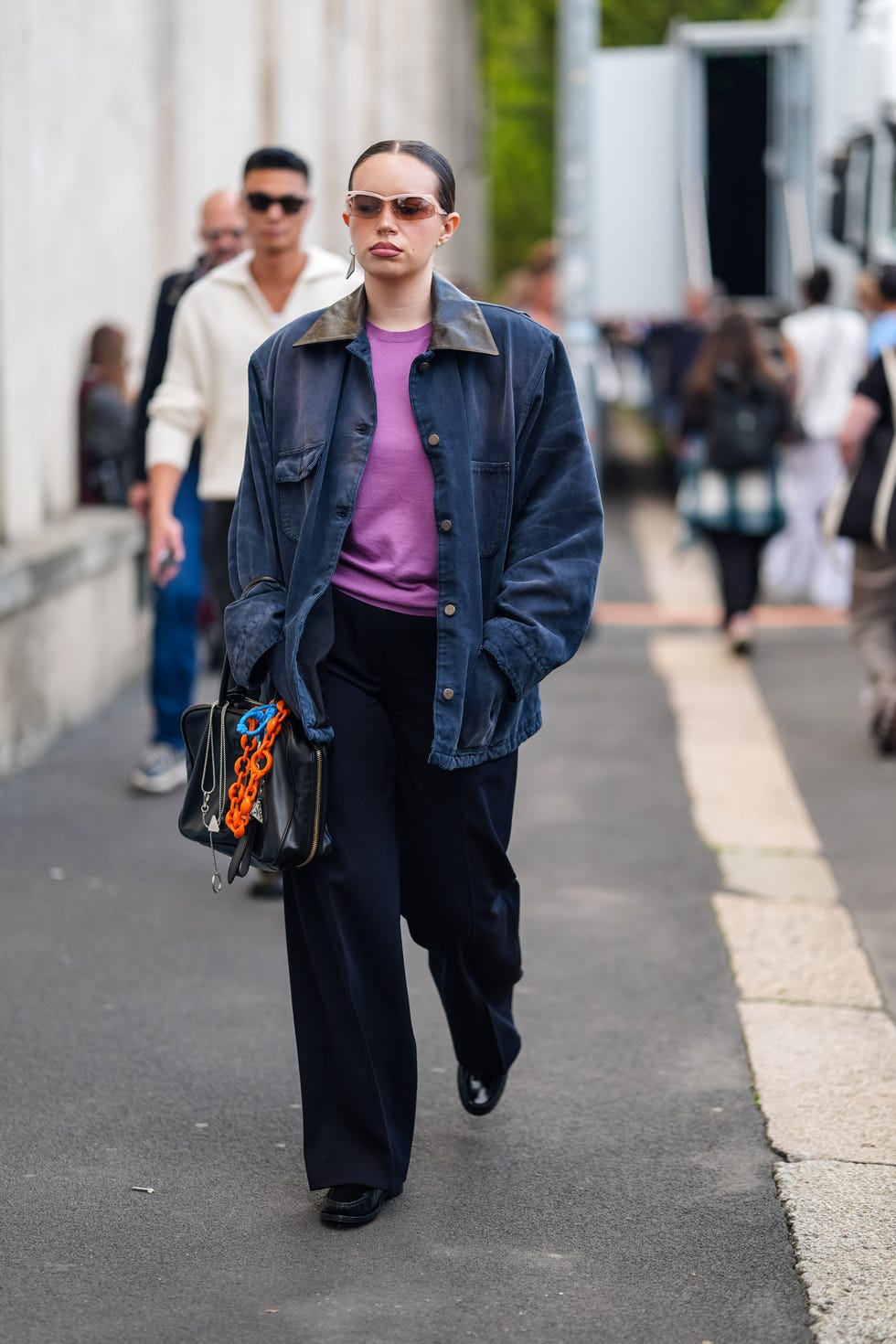 milan, italy september 19 a guest wears dark brown sunglasses, silver earring, dark pink sweater, navy blue oversized jacket, shiny black leather bag, bag charms, black loose pants, shiny black loafer moccasin leather shoes, outside prada, during the milan fashion week springsummer 2024 2025 on september 19, 2024 in milan, italy photo by edward berthelotgetty images