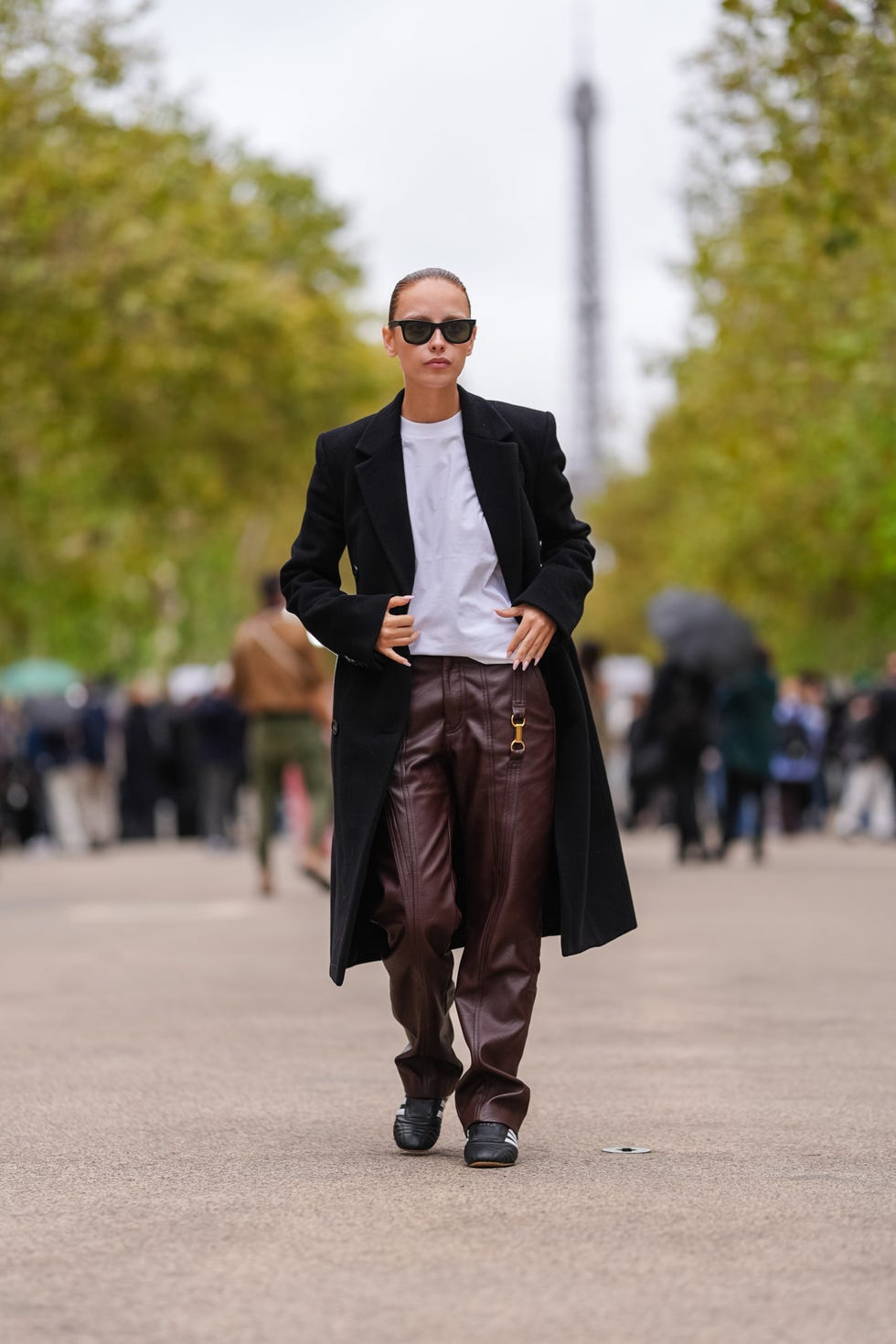 paris, france september 30: a guest wears black sunglasses, white oversized shirt, black coat, shiny black leather pants, black sneakers shoes, outside stella mccartney, during the paris fashion week spring/summer 2025 on september 30, 2024 in paris, france (photo by edward berthelot/getty images)