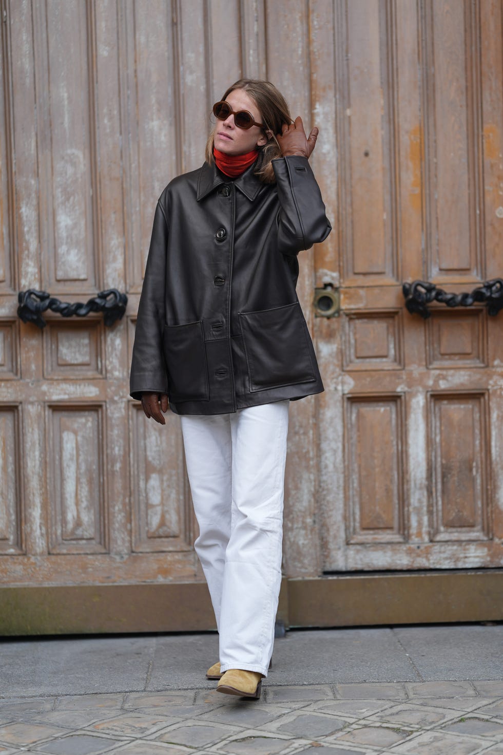 paris, france september 28 a guest wears dark brown sunglasses, bright red turtle neck long sleeve shirt, shiny black oversized jacket, dark brown leather gloves, white pants, light brown suede boots, outside hermes, during the paris fashion week springsummer 2025 on september 28, 2024 in paris, france photo by edward berthelotgetty images