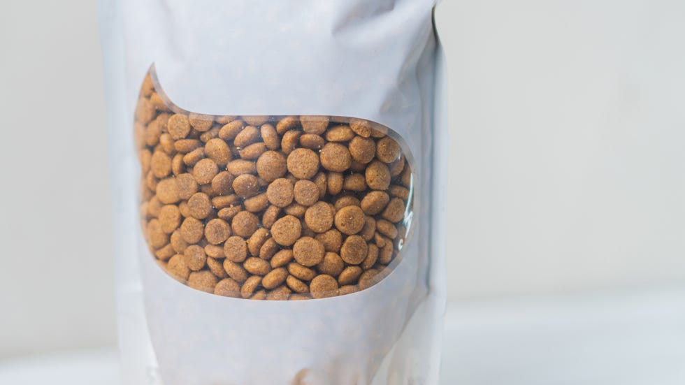 a transparent bag filled with round, brown pet food pellets. the bag has a simple design with a clear window showcasing the contents inside.