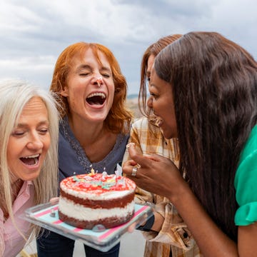 birthday jokes Four happy women celebrating birthday with cake on terrace birthday jokes four happy women of different ages having fun at a birthday party on a cozy terrace, laughing and enjoying a red velvet cake with candles
