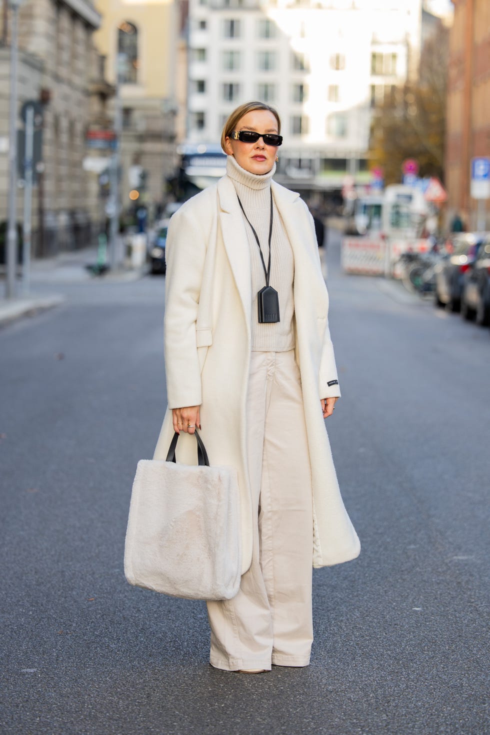 berlin, germany december 03 tina haase wears white maxi coat herskind, white turtleneck sweater, cream wide leg pants beaumont, cream tabi boots maison margiela, cream fauxfur tote bag inwear, black leather keychain necklace podyh, sunglasses balenciaga on december 03, 2024 in berlin, germany photo by christian vieriggetty images