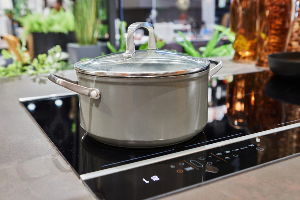 a sleek, metallic saucepan with a glass lid sits on an induction stove, showcasing a modern and minimalistic kitchen design