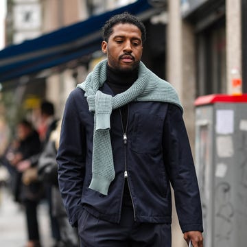 Street Style - Day 3 - Milan Fashion Week - Menswear Fall/Winter 2025-2026 milan, italy january 19: a guest wears black turtleneck long sleeve shirt, dark navy blue half zipped jacket, navy blue relaxed pants, shiny black leather boots, light green sweater around shoulder, outside magliano, during the milan fashion week men’s fall/winter 2025 2026 on january 19, 2025 in milan, italy. (photo by edward berthelot/getty images)