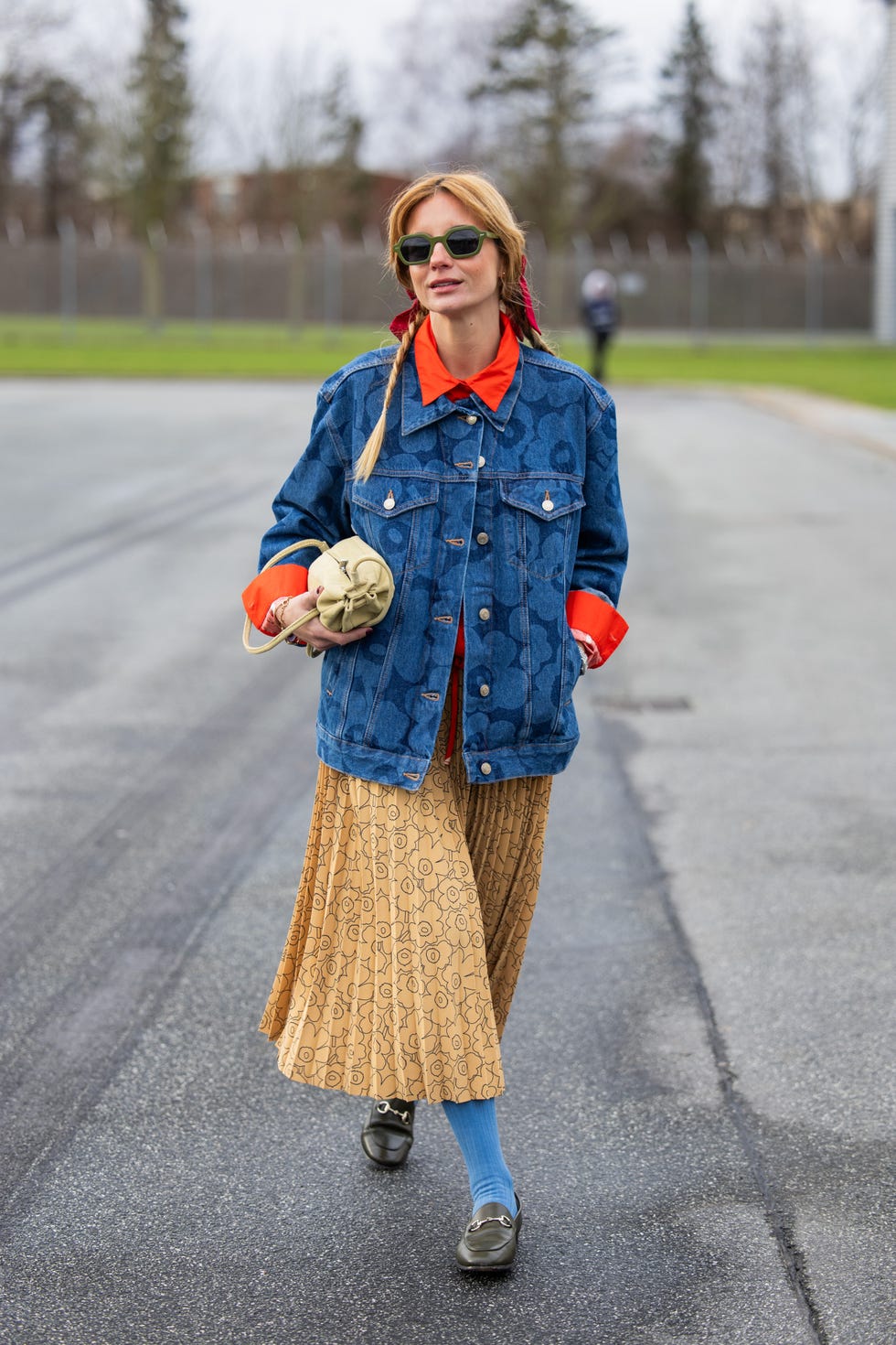 individual wearing a denim jacket red shirt patterned skirt and blue socks