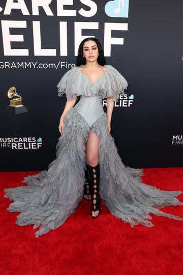 fashionable individual at a red carpet event wearing a dramatic gray gown with ruffles