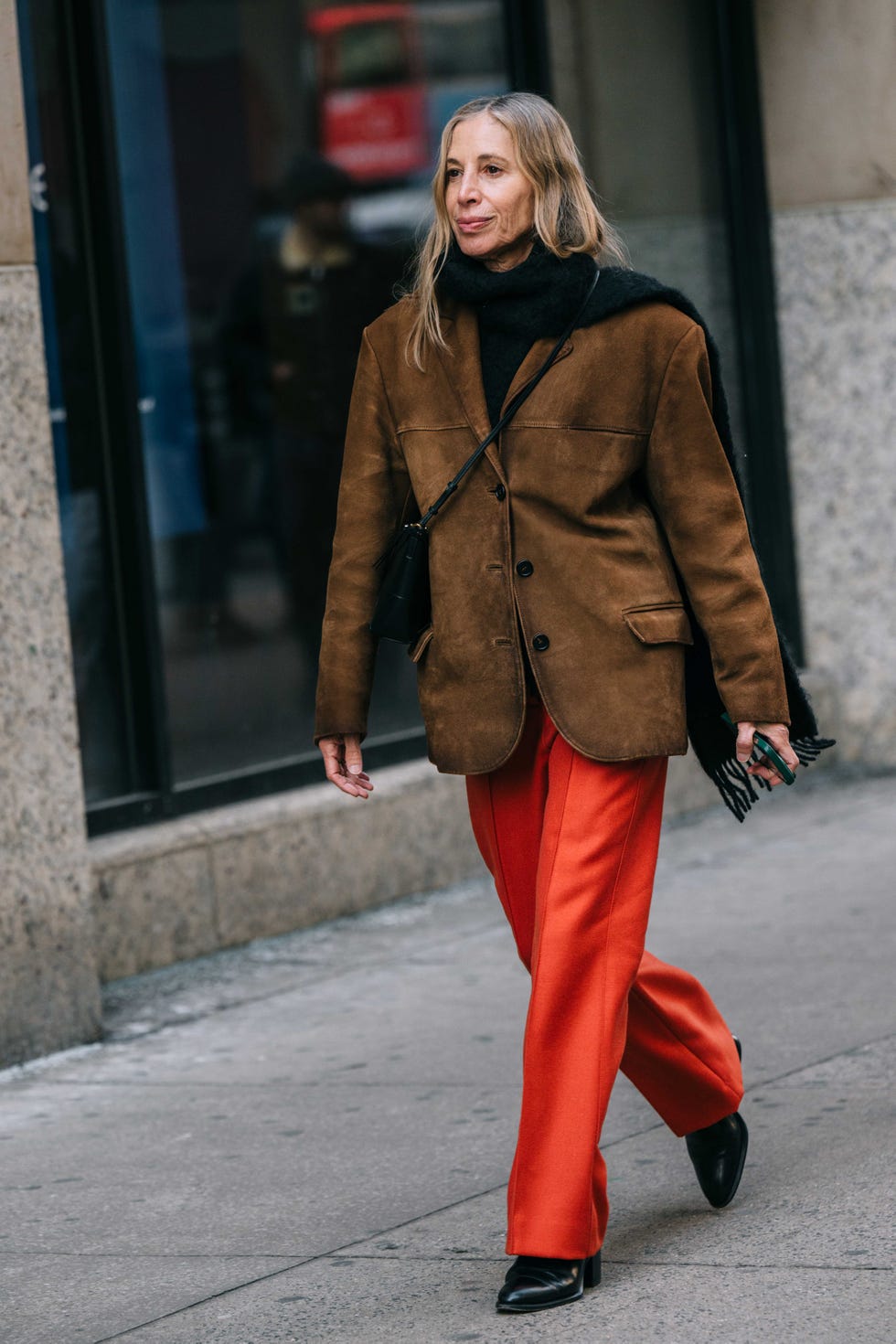 Person walking on the street wearing a brown jacket and orange trousers