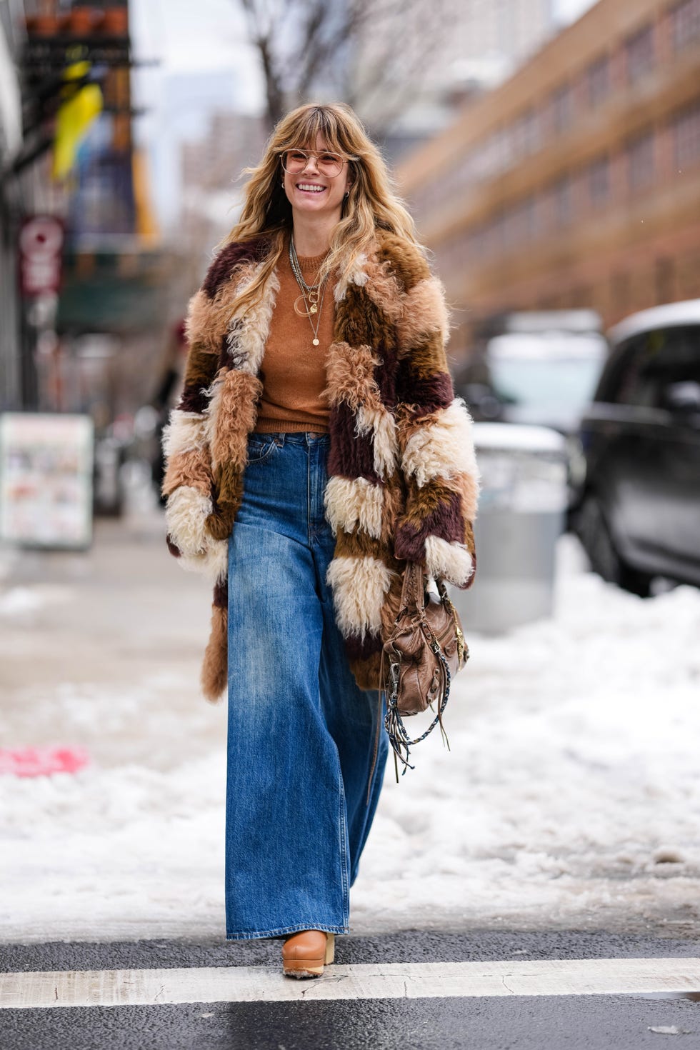 new york, new york february 09 a guest wears light brown sunglasses, dark brown light brown cream patch work faux fur coat, dark brown sweater, silver layered necklaces, navy blue high waisted loose flared denim jean pants, dark brown leather bag, light brown heeled boots leather shoes, outside ulla johnson, during the new york fashion week fallwinter 2025 on february 9, 2025 in new york, new york photo by edward berthelotgetty images