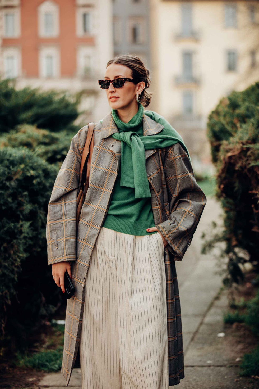 person dressed in layered clothing standing outdoors in an urban setting