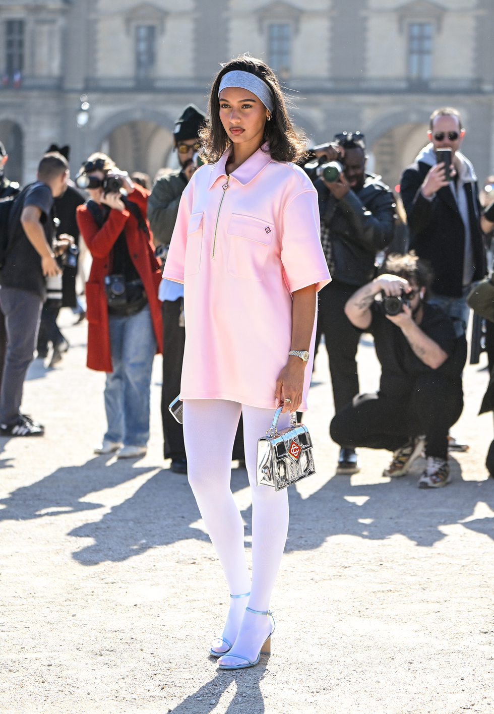 paris, france march 05: a guest is seen wearing a pink casablanca shirt dress, white leggings, casablanca light blue heels and casablanca silver metallic bag and gray headband outside the casablanca show during the womenswear fall/winter 2025/2026 as part of paris fashion week on march 05, 2025 in paris, france. (photo by daniel zuchnik/getty images)