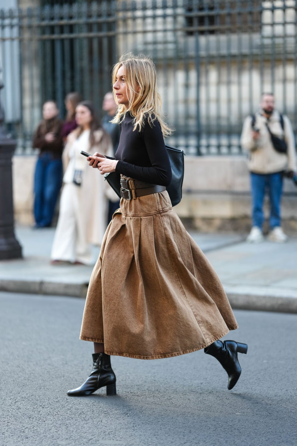 paris, france march 08: a guest wears black long sleeve sweater, light brown high waisted denim jean maxi skirt, shiny dark brown layered leather belt, black leather tote bag, shiny black heeled boots leather shoes, outside paloma wool, during the paris fashion week womens fall/winter 2025 2026 on march 8, 2025 in paris, france. (photo by edward berthelot/getty images)