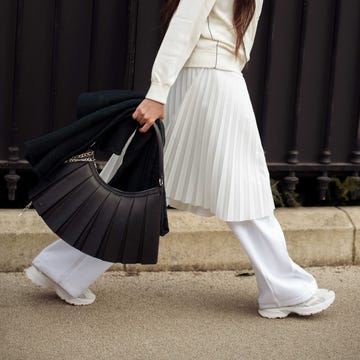 A fashionable individual walking outdoors with a unique handbag and clothing A fashionable individual walking outdoors with a unique handbag and clothing