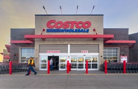 calgary, alberta, canada. apr 10, 2025. exterior shot of a costco wholesale store at dusk with "costco wholesale" signage and people entering, exiting. shopping carts visible