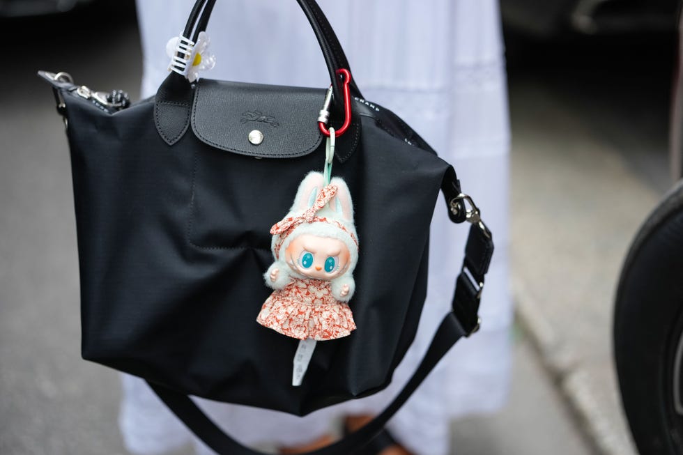 milan, italy june 21: sarah sophia franco wears black longchamps le pliage energy s eco nylon bag, light green labubu from the have a seat collection ququ, custom cream and dark red vegetable pattern/print sundress and matching headband, outside paul smith, during the milan fashion week mens spring/summer 2026 on june 21, 2025 in milan, italy (photo by edward berthelot/getty images)