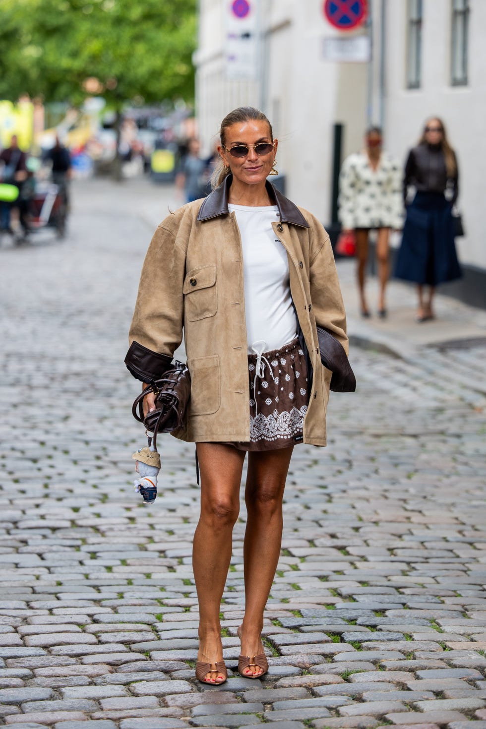 copenhagen, denmark august 04: janka polliani wears beige suede jacket, white shirt, brown skirt with dots print, sunglasses, brown bag with wakuku puppet outside freya dalsjø during copenhagen fashion week day one on august 04, 2025 in copenhagen, denmark. (photo by christian vierig/getty images)