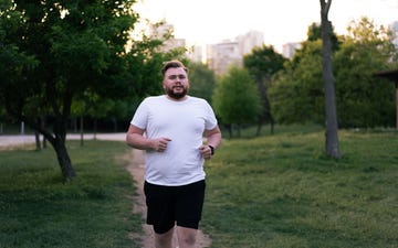 determined overweight man jogging in a park, embracing a healthy lifestyle through exercise and physical activity