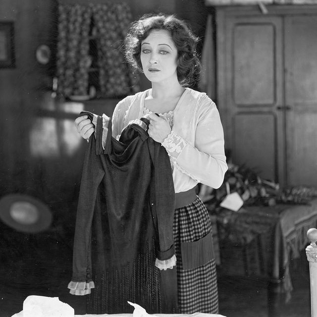 woman holds a dress and looks forlorn in an unidentified film still