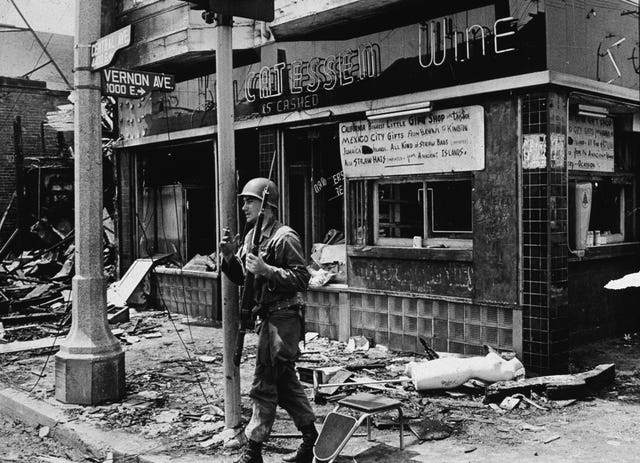 an armed national guard patrolman leans against a street sign, smoking a cigarette and standing in rubble following the watts riots, los angeles, california, august 1965 photo by hulton archivegetty images