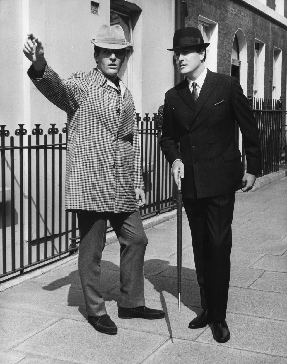 2nd june 1966  two of the suits designed by members of the british menswear guild, on show at a reception held in london to welcome derek rose, the guilds new chairman jim ryan left models a check raincoat by aquascutum ltd, with a corduroy hat by christy  co john fenton wears a double breasted suit by simpson daks, with six buttons  photo by keystonegetty images