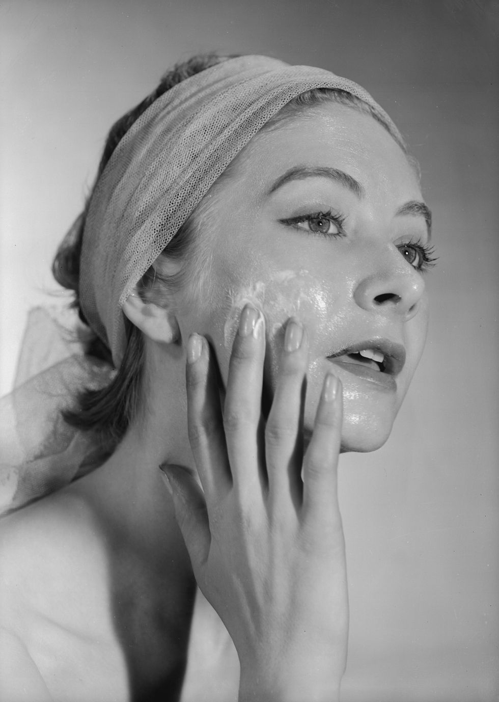 17th december 1952 a woman, her hair tied back with a bandeau, applies cream to her face photo by chaloner woodsgetty images