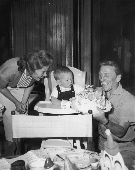 vintage birthday photos 23rd november 1956: american actor kirk douglas kneels down beside his son peters crib with a birthday cake decorated in zoo animals during his first birthday party. peter is reaching toward the cake as anne buydens, douglass second wife, looks on and laughs. (photo by hulton archive/getty images)