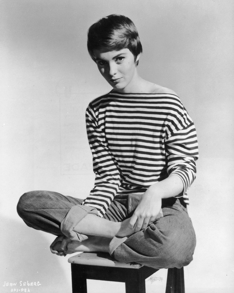 circa 1965 promotional portrait of american actor jean seberg 1938 1979 sitting barefoot and cross legged on a stool, wearing rolled blue jeans and a french striped sailor jersey pulled off one shoulder photo by hulton archivegetty images