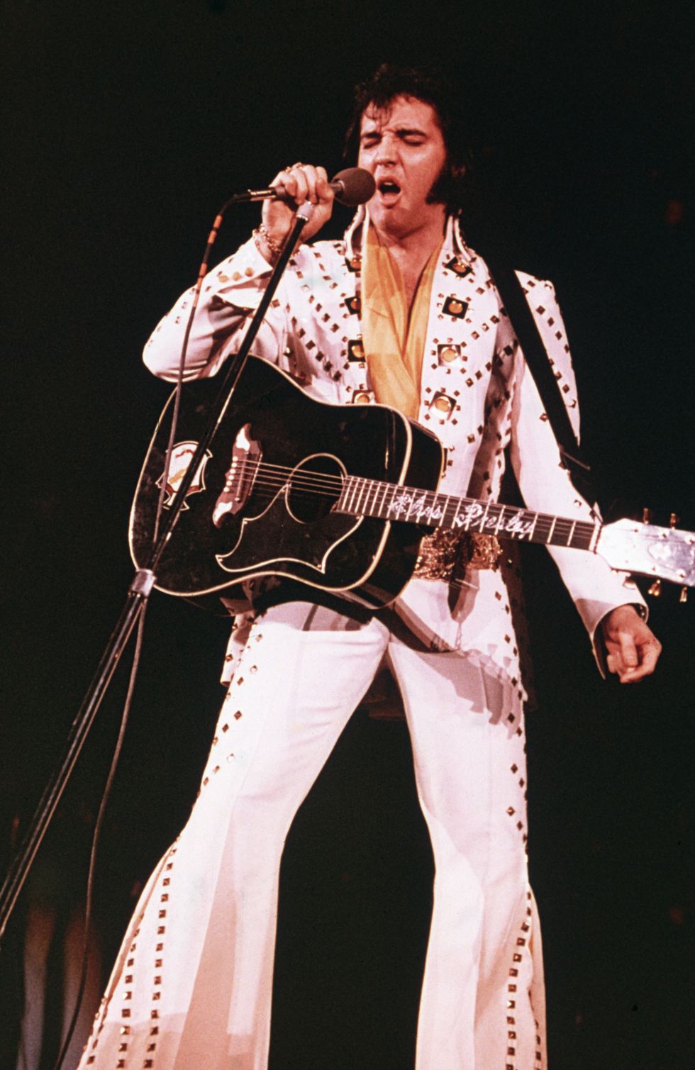 circa 1975  american rock singer elvis presley 1935   1977, wearing a white rhinestone studded suit and strapped guitar, singing into a microphone with his eyes closed  photo by fotos internationalgetty images