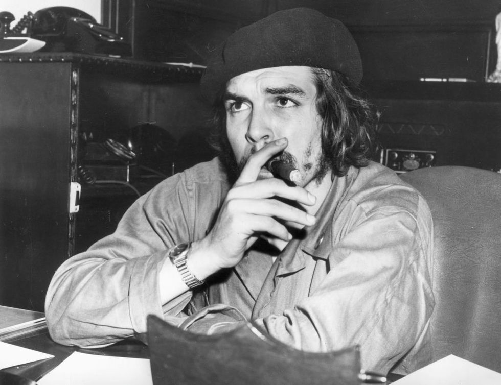 1959  argentine born cuban revolutionary leader and economic advisor ernesto che guevara 1928   1967 sits at a desk and smokes a cigar, wearing military fatigues and a beret after aiding fidel castros successful overthrow of the batista regime, guevara served as economic advisor in castros administration  photo by hulton archivegetty images