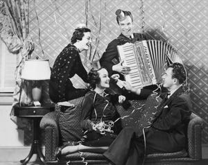 circa 1935 two couples celebrate new years with confetti, streamers, party hats, smoking and accordion music on their living room sofa photo by hulton archivegetty images