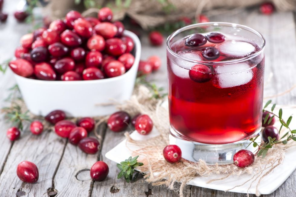 Glass of fresh cranberry juice and a bowl of cranberries