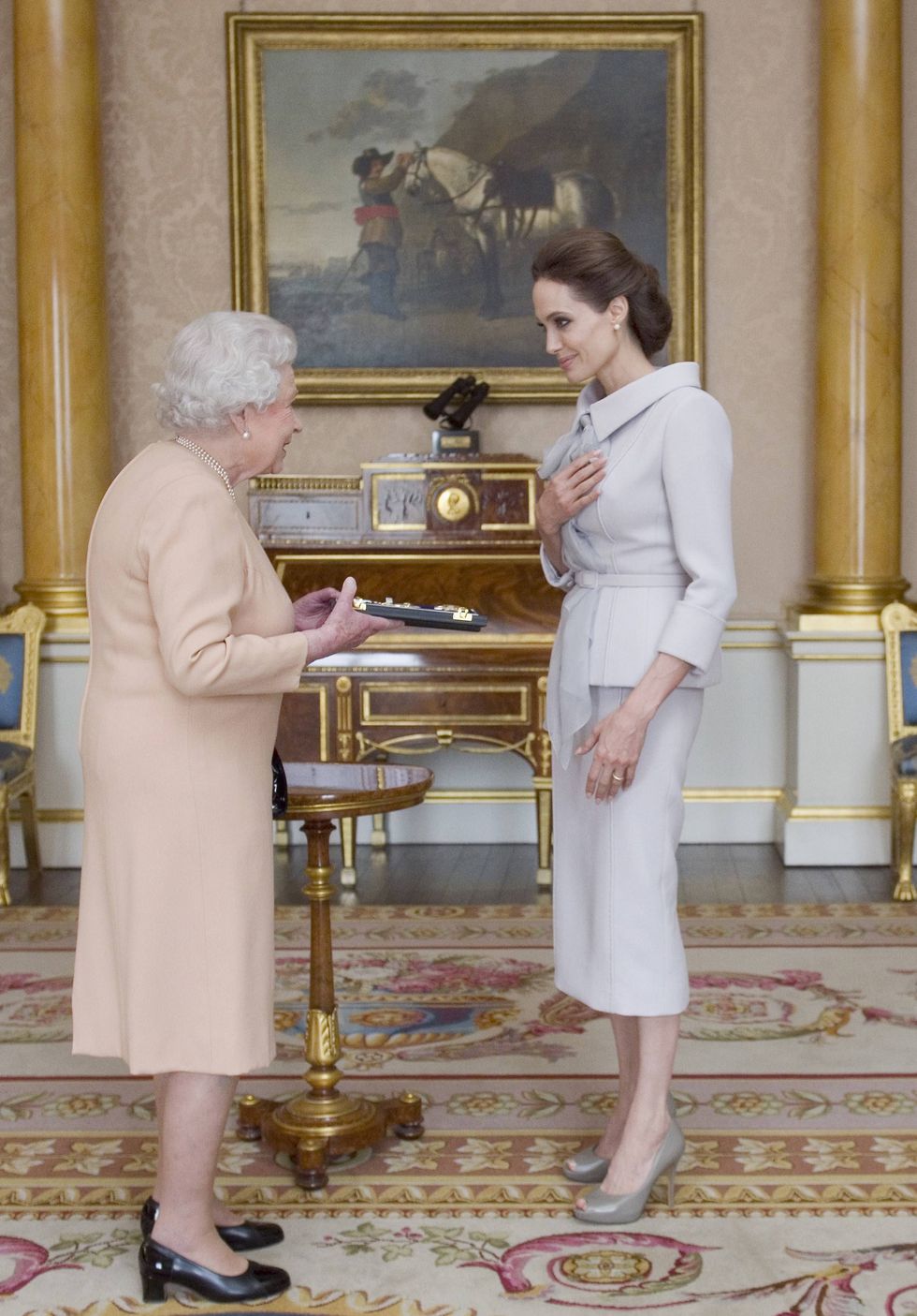 us actress angelina jolie r is presented with the insignia of an honorary dame grand cross of the most distinguished order of st michael and st george by britain's queen elizabeth ii in the 1844 room at buckingham palace in central london, on october 10, 2014 angelina jolie was awarded an honorary damehood dcmg for services to uk foreign policy and the campaign to end war zone sexual violence afp photoanthony devlinpool photo credit should read anthony devlinafp via getty images